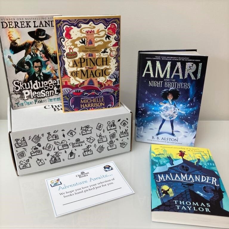 A display featuring four books and a box from 'Chestnut Books.' The books are 'Skulduggery Pleasant' by Derek Landy, 'A Pinch of Magic' by Michelle Harrison, 'Amari and the Night Brothers' by B. B. Alston, and 'Malamander' by Thomas Taylor. The box i